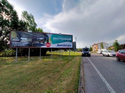 Via città di Ferrara con traffico e poster con pubblicità