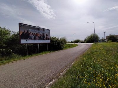 Via città di Ferrara con traffico e poster 6X3 con pubblicità